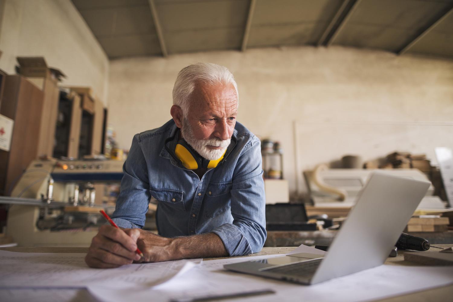 A longtime owner at the workbench in his shop, working through plans on a laptop